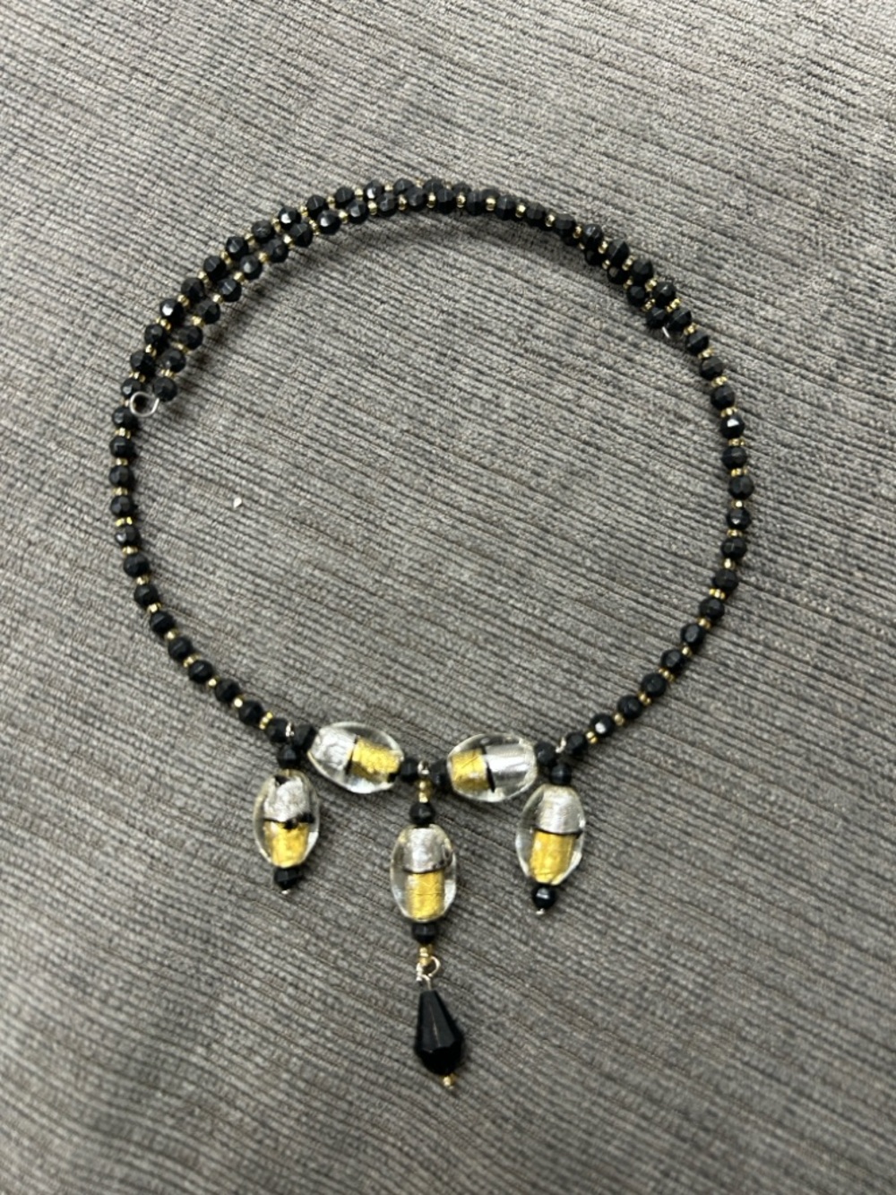 Handcrafted beaded necklace dark beads and central clear and gold glass charms.